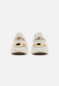 Witte sneakers met een textuurstof bovenkant en een gewatteerde hiel, voorzien van een glanzende gouden accenten en een gevoerde zool. Plat rubberen buitenzool.