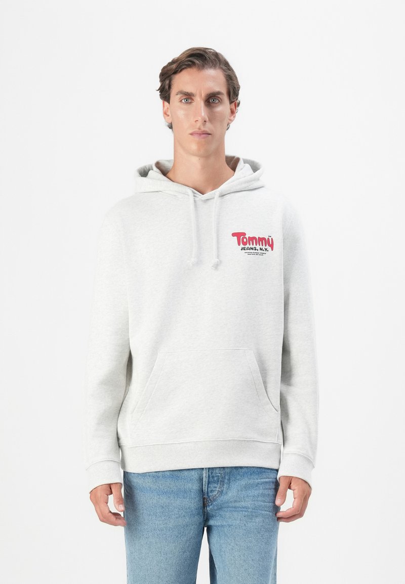 Grå hætte sweatshirt lavet af blød stof, med en frontlomme og rød "Tommy Jeans"-logo. Tætsiddende manchetter ved ærmerne og taljen.