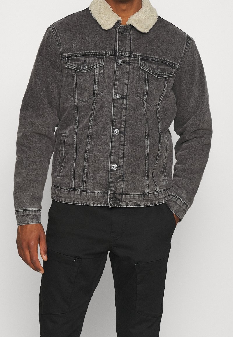 Denimjack met een verweerde zwarte kleur en een zachte crème-kleurige kraag, voorzien van borstzakken, knopen aan de voorkant en een gestructureerde pasvorm. Geverfd textiel.