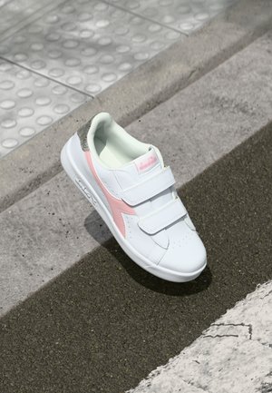 Basket blanc avec des accents rose et argent, fabriquée en matériau synthétique lisse. Présente deux sangles Velcro et une boîte à orteils perforée pour une meilleure ventilation.