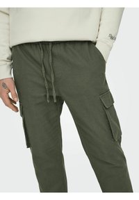 Olivgrüne Cargo-Hosen mit einem Kordelzugbund, seitlichen Taschen und einem lockeren Schnitt. Hergestellt aus weichem, strukturiertem Stoff.