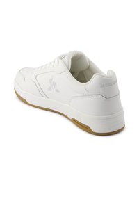 Hvide sneakers lavet af læder, med rund tå, snørelukning og en gummigummiså, samt et prægede logo på hælen.