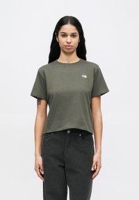 Olívazöld rövid ujjú pamut póló, kerek nyakkivágással és egy kis fehér logóval a bal mellrészen.