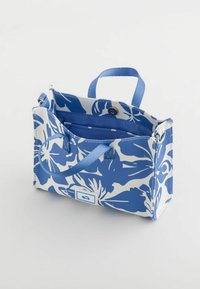 Blomster tote bag med et blåt og hvidt mønster, rektangulær form, top-håndtag og blåt interiør. Har en lås lukning og lommer.
