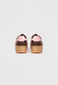 Baskets marron avec des accents roses et brillants, présentant une texture en daim, une semelle épaisse et un design épuré. Conçues pour le confort et le style.