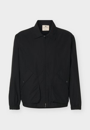 Schwarze Jacke mit Reißverschluss, Kragen, elastischen Bündchen und zwei vorderen Klappentaschen mit Druckknöpfen, auf weißem Hintergrund dargestellt.