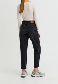 Jeans negros de talle alto con pierna ajustada, que presentan un tejido texturizado, puños enrollados y un parche de cuero de la marca en la parte trasera de la cintura.