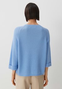 Pull en tricot côtelé bleu clair, à manches trois-quarts et avec des poignets roulés. Présente une coupe décontractée et un col rond.