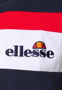 Bavlněné tričko s proužky v námořnické modři, červené a bílé barvě, s vyšívaným logem "ellesse" a polokruhovým akcentem v oranžové a žluté barvě.