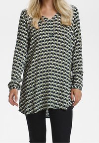 Tunique à manches longues avec un col en V, présentant un motif géométrique en vert, marine et crème. Tissu léger avec une coupe décontractée et un ourlet arrondi.