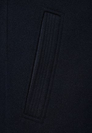 Ciemnoniebieska tkanina z pionowym prostokątnym detalem ściegowym, ukazująca fakturę i subtelne liniowe wzory w wełnianym materiale.