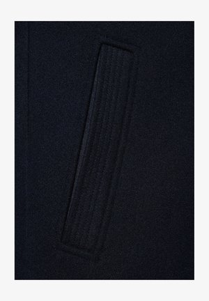 Ciemnoniebieska tkanina z pionowym prostokątnym detalem ściegowym, ukazująca fakturę i subtelne liniowe wzory w wełnianym materiale.