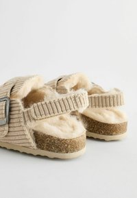 Beiga sandaler med en ribbad tygöverdela, fluffigt foder och två justerbara remmar. Korkstrukturerad sula med en lätt gummibas för bra grepp.