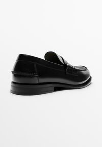 Sorte læderloafers med en glat finish, rundet tå og synlige syninger. Har en lav, flad hæl og en dekorativ rem over foran.