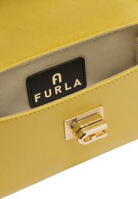 Gele leren handtas met een gestructureerd oppervlak, voorzien van een gouden sluiting en een zwart Furla-logo label op de binnenvoering.