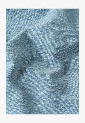 Light blue denim fabric with visible diagonal weave texture and soft folds creating shadows and highlights.