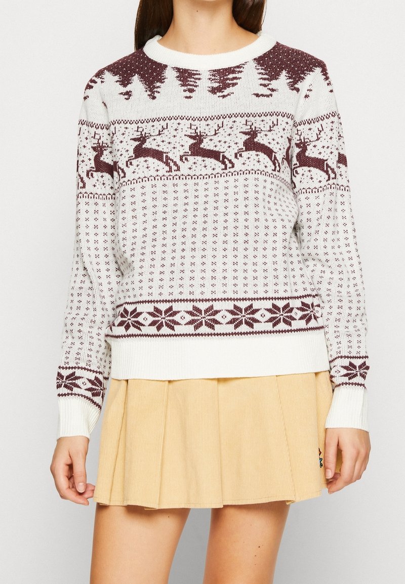 Pull en tricot blanc et bordeaux. Présente un motif festif avec des rennes, des arbres et des flocons de neige. Manches et ourlet côtelés, encolure ronde.