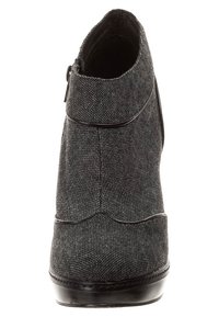 Botín negro de tela con superficie texturizada y diseño con forma de onda. Presenta una cremallera en el lateral y una suela negra brillante.