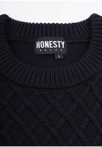 Musta neulepaita, jossa on tekstuurinen timanttikuvio, ribbireunalla varustettu pyöreä kaulus, merkitty "HONESTY RULES", koko L.