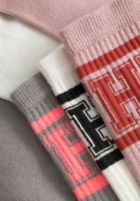Gekleurde sokken: roze, wit, grijs en zwart. Geribbelde textuur met opvallende grafische letters in contrasterende kleuren.