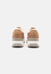 Sneakers in suede marrone con fodera in pelliccia sintetica color crema, con dettagli bianchi, scritta "1973" e tallone imbottito per un maggiore comfort.