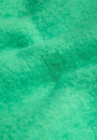 Lysegrønt tekstureret materiale med et blødt, fluffet udseende, der har subtile variationer i nuance og dybde over hele overfladen.