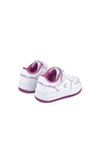 Sneakers bianchi con dettagli rosa, cinturini in velcro e una suola in gomma texturizzata. Presentano un logo sul lato e cuciture a contrasto.