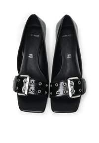Chaussures en cuir noir à talons hauts avec un bout carré, dotées d'une sangle à boucle brillante et de quincaillerie en argent avec des découpes circulaires.