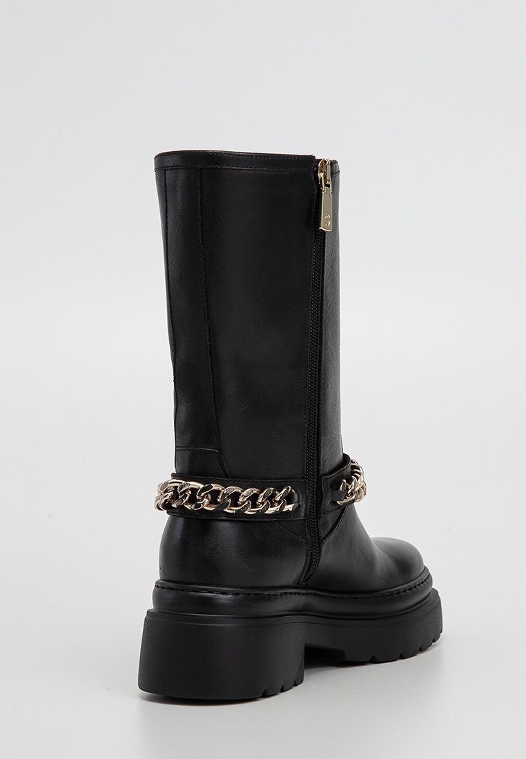 Schwarze Lederkniehohe Stiefel mit robuster Sohle, seitlichem Reißverschluss und goldener Kettendetail um den Knöchel. Glatte Textur und minimalistisches Design.
