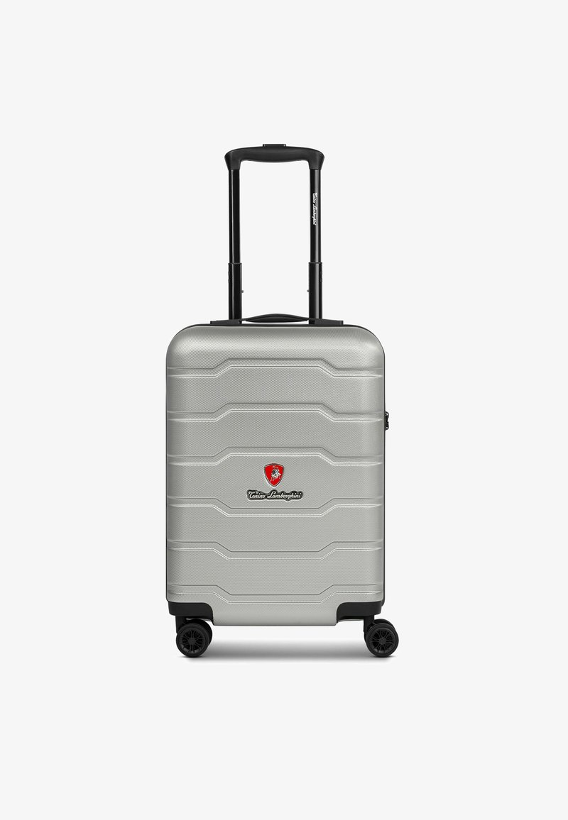 Maleta rígida plateada con superficie texturizada, asa retráctil y cuatro ruedas negras. Presenta un logo en rojo y negro.