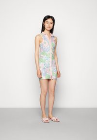 Vestido floral com colarinho rosa e fecho de botões, apresentando padrões de flores azul claro e verdes sobre um fundo rosa pastel. Sandálias slide rosas.