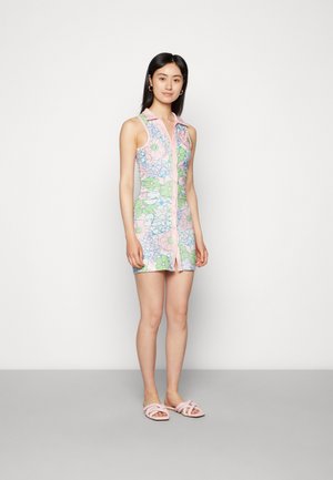 Vestido floral com colarinho rosa e fecho de botões, apresentando padrões de flores azul claro e verdes sobre um fundo rosa pastel. Sandálias slide rosas.