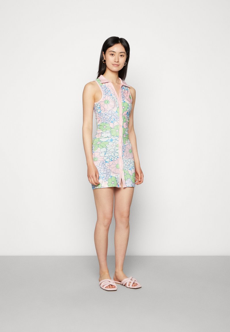 Vestido floral com colarinho rosa e fecho de botões, apresentando padrões de flores azul claro e verdes sobre um fundo rosa pastel. Sandálias slide rosas.