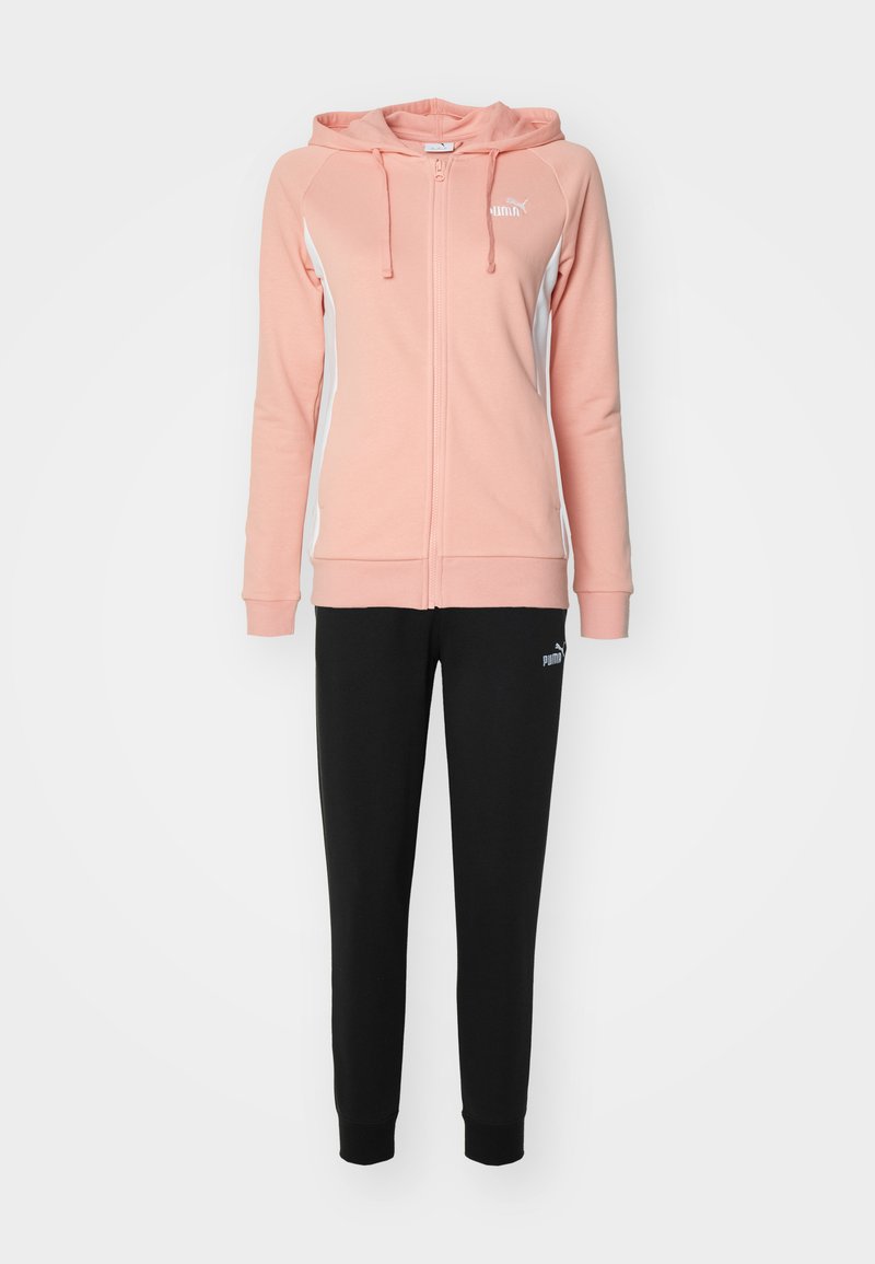 Tuta Puma composto da una felpa rosa con zip e dettagli bianchi, abbinata a pantaloni neri tapered. Il tessuto è morbido, con una consistenza liscia e un dettaglio con il logo.