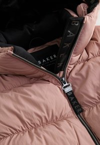Giacca trapuntata rosa chiaro parzialmente zipata, che mostra l'interno nero e il tirante della zip nero con il marchio "Baker".