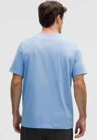 Vaaleansininen puuvillainen t-paita, jossa on lyhyet hihat ja pyöreä pääntie, sileä pinta ja suora helma.