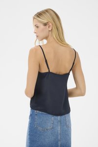 Navy blue satin camisole with thin adjustable straps, smooth texture, and a slightly relaxed fit, paired with a denim skirt.