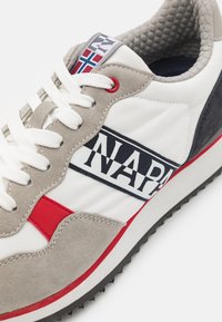 Bílé tenisky s šedou semišovou a námořnickou akcentací. Obsahují červený detail, tmavou podrážku a výrazné branding "NAPA" na boku. Texturovaný interiér.