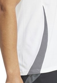 Weißes Sportshirt mit einer texturierten grauen Seitenbahn, ausgestattet mit glattem Stoff und einem Rundhalsausschnitt. Das Design umfasst kontrastierende Farben.