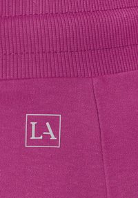 Fuchsia-pinke Sweatpants mit einem gerippten Bund und einem silbernen "LA"-Logo an der Seite. Weicher Stoff mit einer glatten Textur.