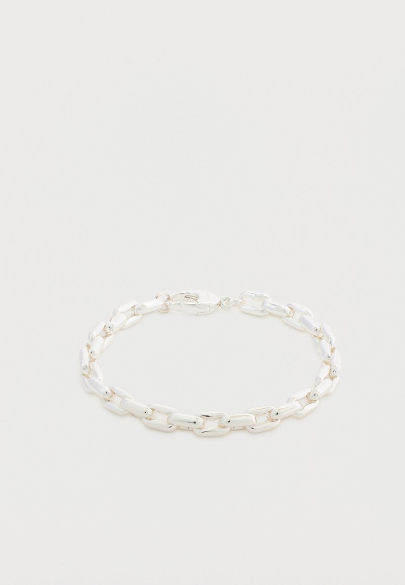 Bracelet en chaîne argentée avec des maillons ovales allongés et une fermeture à mousqueton sur une surface blanche.