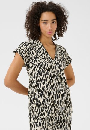 Haut à manches courtes noir et ivoire avec un décolleté en V, présentant un motif abstrait audacieux et une coupe décontractée, fabriqué à partir d'un tissu léger.