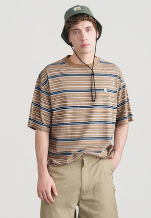 Καφέ και ναυτικά ριγέ υπερμεγέθη μπλουζάκι, βαμβακερό ύφασμα, κοντά μανίκια, στρογγυλή λαιμόκοψη. Συνδυασμένο με ταμπά cargo σορτς και πράσινο καπέλο τύπου bucket.