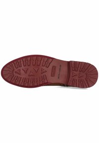 Semelle de chaussure en caoutchouc avec une base rouge, comportant un motif de semelle pour une meilleure adhérence, et une marque en relief sur le côté. Texture lisse dans l'ensemble.