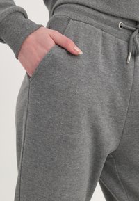 Hallhalli puuvillased dressipüksid küljetaskutega ja elastse vöökohtaga, millel on pael. Kanga tekstuur on pehme ja sile.