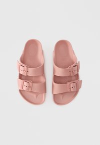 Rosa gummisandaler med to justerbare spenner, formet fotseng og flat såle. Jevn tekstur uten synlige mønstre eller detaljer.