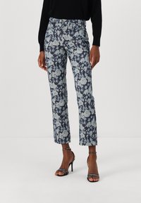 Pantaloni florali în nuanța bleumarin, cu motive de trandafiri în nuanța albastră deschisă și albă. Au un croi drept, design cu cinci buzunare și fante pentru curea.