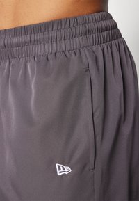 Kratke sportske hlače u boji ugljena s elastičnom strukom i bočnim džepovima. Sadrže detalj s bijelim logotipom blizu rubova. Glatka, lagana tkanina.