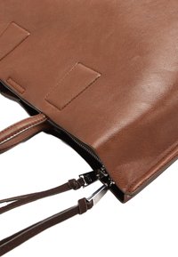 Brązowa torba typu tote z fakturowaną powierzchnią, wyposażona w górne zamknięcie na zamek błyskawiczny, podwójne uchwyty oraz regulowane paski dla większej wszechstronności.