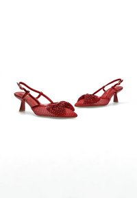 Zapatos slingback rojos con un patrón texturizado, que presentan un acento de cuentas en la parte frontal y un tacón de aguja de altura media.